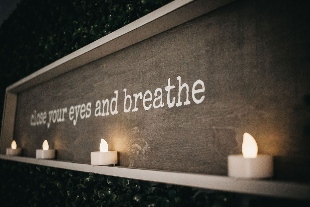 candle lighted sign reading "close your eyes and breathe" 