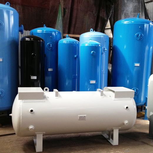 A variety of cylindrical pressure vessels in different sizes and colors, primarily blue and one in black, arranged in a warehouse setting. The tanks feature multiple connection points and inspection labels, and are designed for industrial use in systems requiring pressurized storage, prominently displayed for sale or rental services.