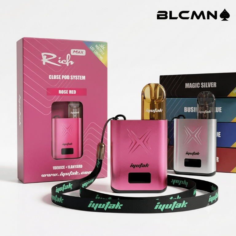 A square 1080x1080 pixel product display showcasing the Iyutak Rich Max Closed Pod System against a clean white backdrop. On the left stands the vibrant rose-pink retail box featuring the "Rich Max" holographic branding. In the center sits the metallic rose-pink box-style vape mod attached to a heavy-duty black fabric lanyard printed with green "iyutak" lettering, while a matching silver metallic mod rests next to it. The top right corner features the sharp black BLCMN logo with its iconic spade emblem.